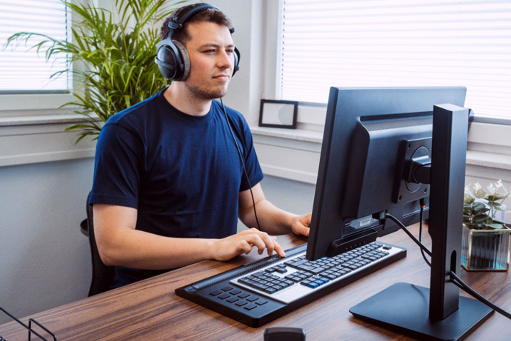 mann på kontor med headset sitter og jobber på activator pro sort slank  leselist med QWERTY tastatur.foto